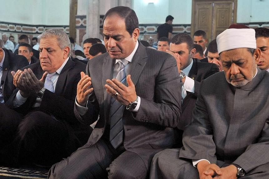Egypt's President Abdel Fattah al-Sisi (centre), along with Grand Imam of al-Azhar Shiekh Ahmed el-Tayeb (right) and Prime Minister Ibrahim Mahlab (left) performing prayers on the Muslim holiday of Eid al-Adha, or feast of sacrifice, in the capital C