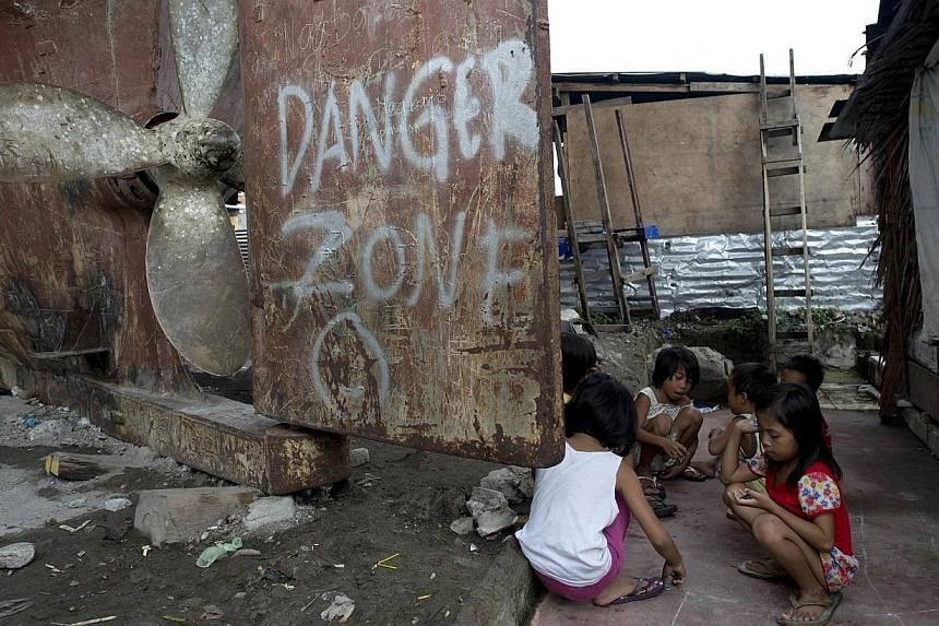 This photo taken on Oct 11, 2014 shows children playing near a ship (left) that was washed ashore near Tacloban during the deadly storm in November, 2013.&nbsp;Authorities in a Philippine city ravaged by Super Typhoon Haiyan were Wednesday faced with