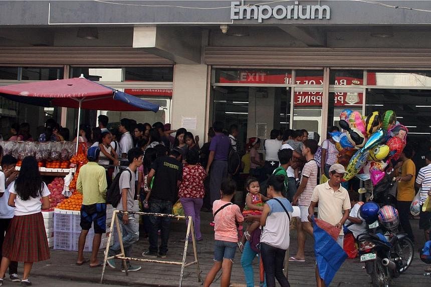 Residents crowd the entrance of a grocery store in Tacloban City, central Philippines on Dec 3, 2014, ahead of the landfall of Typhoon Hagupit.&nbsp;The Philippine government on Wednesday sent food and medical supplies to central provinces on the pat