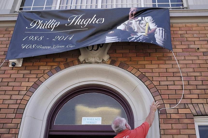 A local resident strings up a banner in honour of Australian cricketer Phillip Hughes in Macksville as his hometown prepares for his funeral, on Dec 2, 2014. -- PHOTO: REUTERS