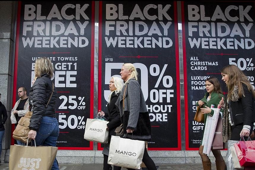 Shoppers are pictured walking past Black Friday advertising in shop windows on Oxford Street in central London on Nov 28, 2014.British department store chain John Lewis and other retailers reported record sales last week as shoppers surged into store