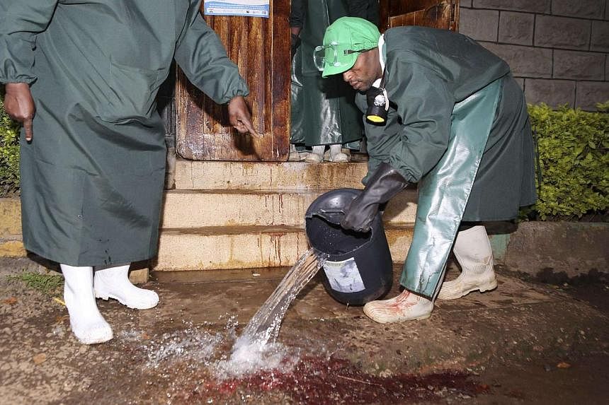 Mortuary workers clean the blood stained floor after receiving the bodies of workers killed at a quarry site in Korome, outside the border town of Mandera, after the bodies were flown to Kenya's capital Nairobi on Dec 2, 2014. Somali al Shabaab Islam