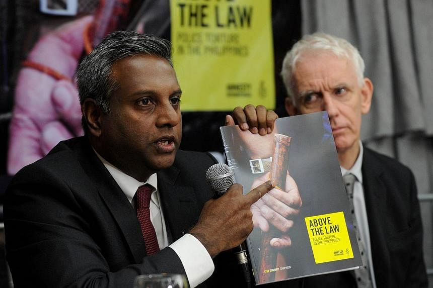 Salil Shetty (left) Amnesty International Secretary-General shows a report of police torture as Steve Crawshaw looks on during the launching of the report of police torture in the Philippines in suburban Manila on Dec 4, 2014.&nbsp;Torture of suspect