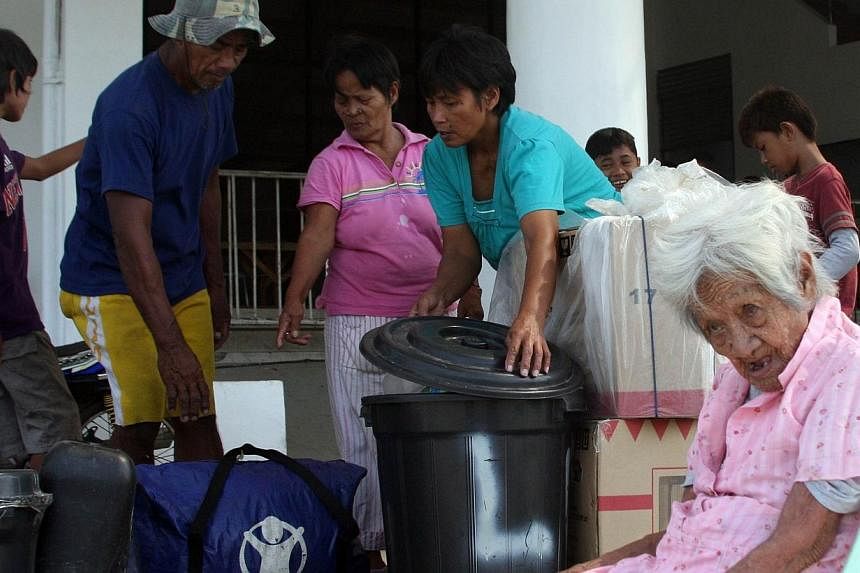 An elderly woman sits while other family members gather their belongings as they arrive at a stadium, serving as a temporary evacuation centre for residents in Tacloban City, central Philippines on Dec 4, 2014, ahead of the arrival of Typhoon Hagupit