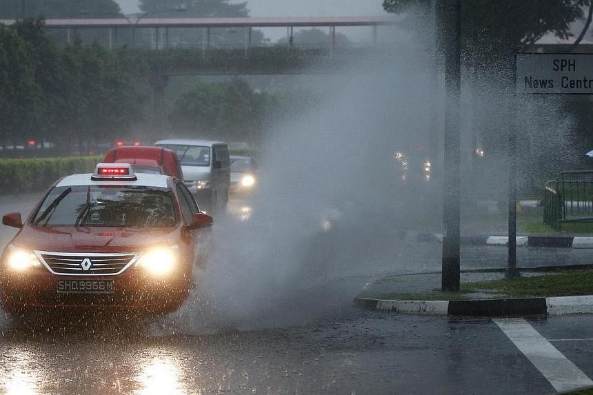 A taxi causes water to splash along Braddell Road on the morning of Dec 4, 2014. -- ST PHOTO: KEVIN LIM