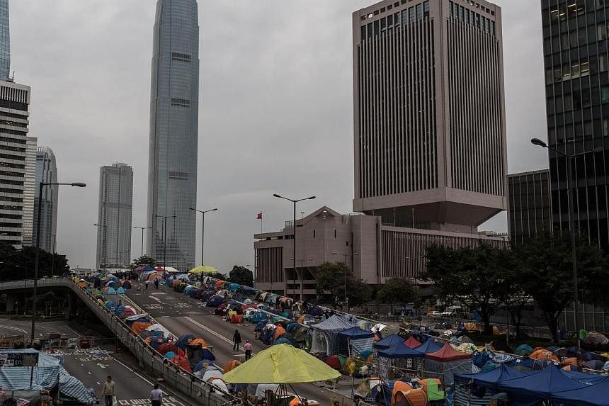 Pedestrians and protesters walk on a section of Harcourt Road, a multi-lane highway through the heart of the financial district currently blocked by pro-democracy protester barricades and hundreds of tents, in the Admiralty district of Hong Kong Kong
