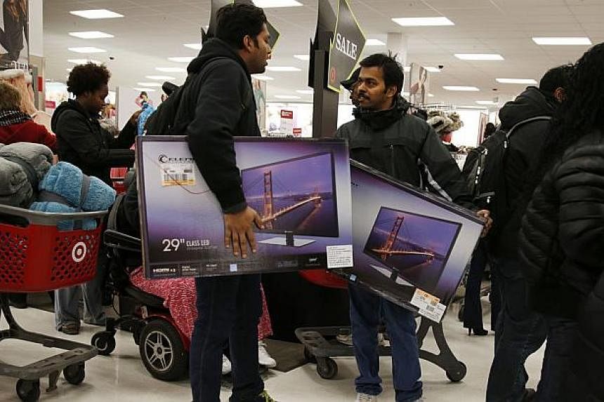 Thanksgiving Day shoppers carry televisions at a Target store in Chicago, Nov 27, 2014. The US economy continued growing in October and November amid widespread optimism about the growth outlook, according to a Federal Reserve report released Wednesd