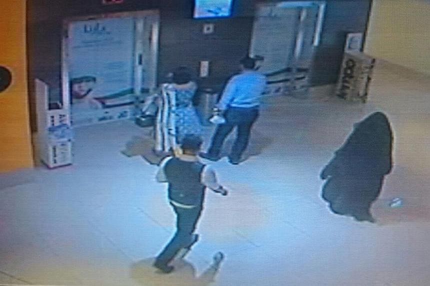 A person (right), dressed in a black robe and suspected in the killing of a US woman at a shopping mall at Al Reem Island in Abu Dhabi is seen in this still image taken from a monitoring camera footage provided by Abu Dhabi Police on Dec 3, 2014. -- 