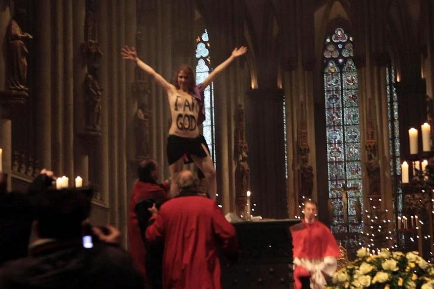 A picture taken on Dec 25, 2013 shows a topless Femen activist displaying the lettering "I am God" on her chest as she demonstrates during a Christmas Day service at the Cologne Cathedral in Cologne, western Germany.&nbsp;A German court Wednesday han