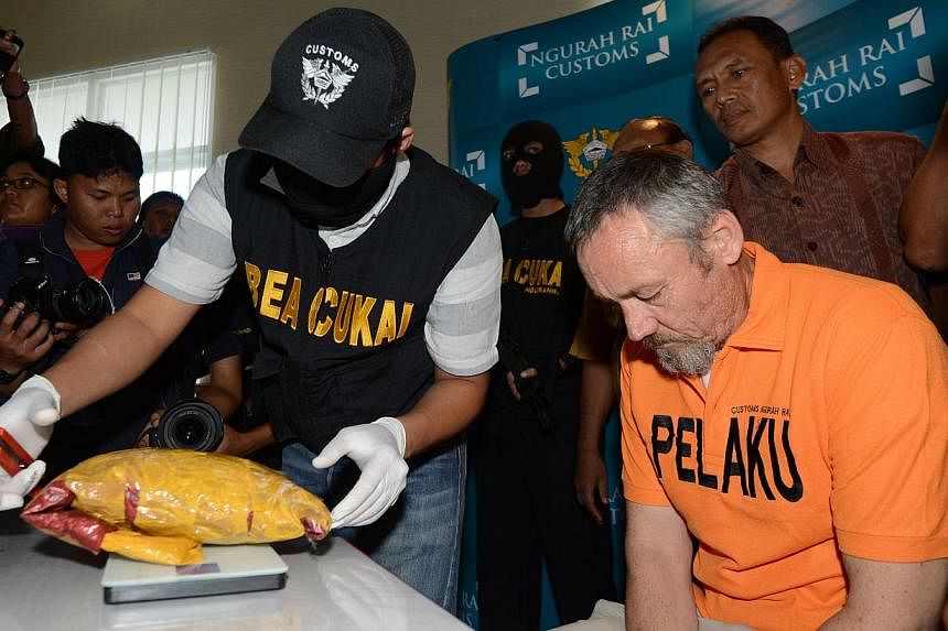 Antony Glen De Malmanche of New Zealand sits as evidence is placed next to him by customs security during a press conference in Denpasar, Bali, on Dec 5, 2014. -- PHOTO: AFP&nbsp;