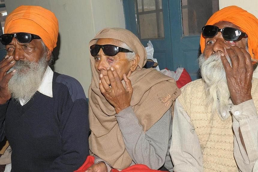 Indian patients Joginder Singh (left), Payar Kaur (centre) and Joginder Singh, who lost their eyesight after undergoing surgery at an eye camp, show their damaged eyes as they sit at a government hospital in Amritsar on Dec 5, 2014.&nbsp;At least 11 
