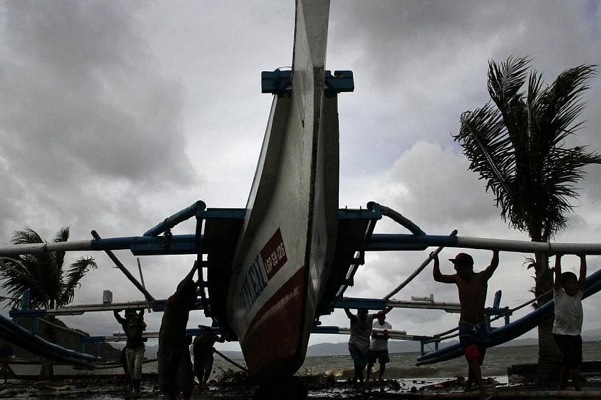 Fishermen carry thier outrigger to higher ground in Legazpi City, south of Manila on Dec 5, 2014, ahead of the landfall of Typhoon Hagupit.&nbsp;The Singapore Civil Defence Force (SCDF) has deployed an officer to the Philippines ahead of Typhoon Hagu