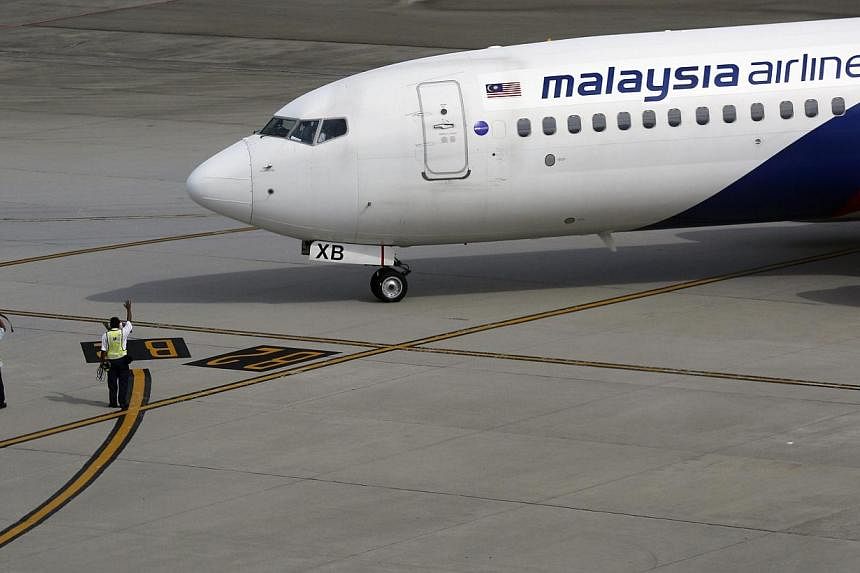 Ground staff wave to a Malaysian Airlines aircraft as it leaves Kuala Lumpur International airport in Sepang outside Kuala Lumpur on Nov 17, 2014.&nbsp;Malaysia Airlines said its shares will be suspended from the country's stock exchange on Dec 15 un