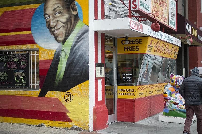 A man walks past a mural of comedian Bill Cosby painted on the side of Ben's Chili Bowl in Washington, DC, Dec 4, 2014. The US Navy has revoked Bill Cosby's title of honorary chief petty officer, citing allegations of sexual abuse against the comedia