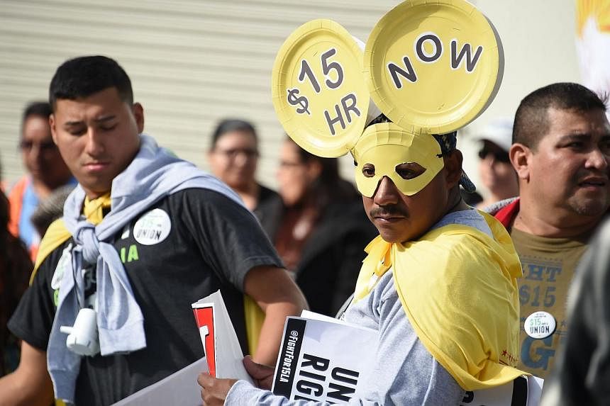 Fast-food workers, health-care workers and their supporters shouting slogans at a rally and marching to demand an increase of the minimum wage to US$15 (S$19.70) an hour, in Los Angeles on Dec 4, 2014. -- PHOTO: AFP