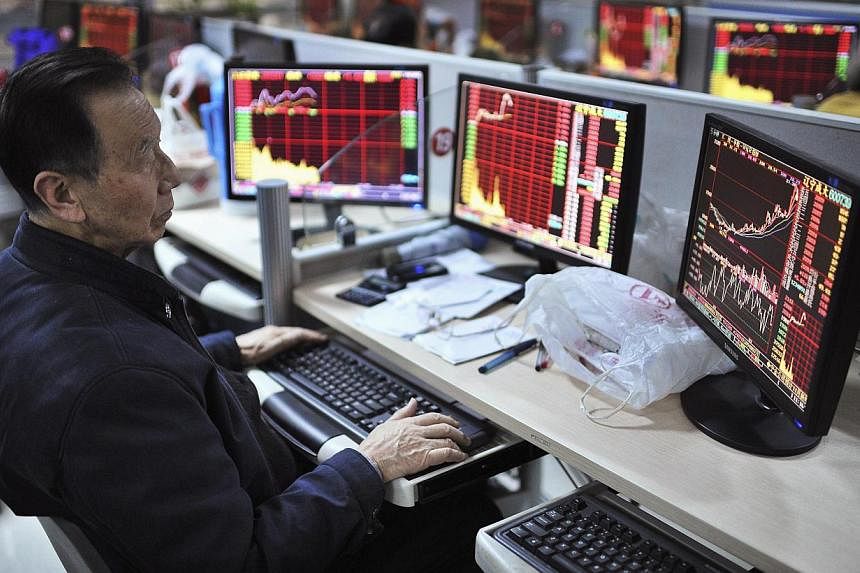 An investor looks at computer screens showing stock information at a brokerage house in Hefei, Anhui province. -- PHOTO: REUTERS