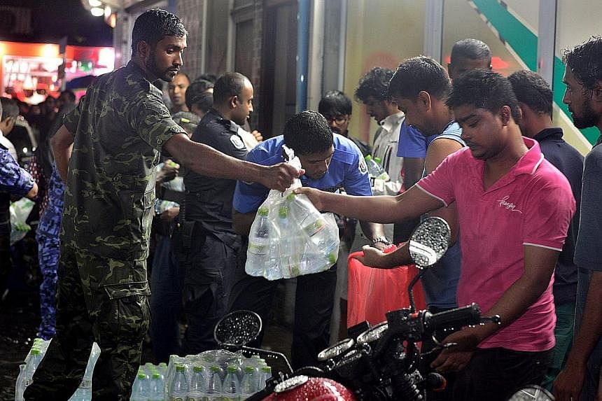Police officials and security personel distribute bottles of water to residents after a fire at a desalination plant affected water supplies in Male on&nbsp;Dec 4, 2014. -- PHOTO: AFP