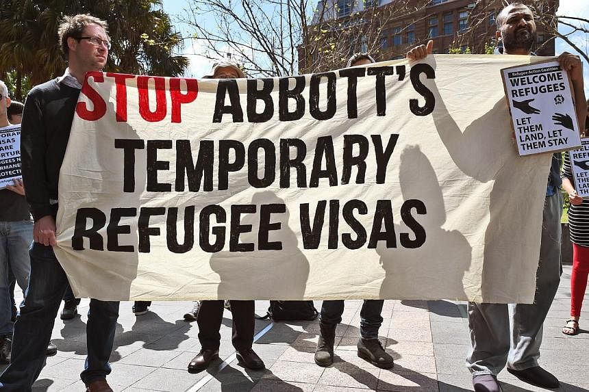 Protesters hold up banners at a rally in Sydney on Sept 26, 2014, opposing Australia's plan to introduce controversial temporary visas for refugees. -- PHOTO: AFP