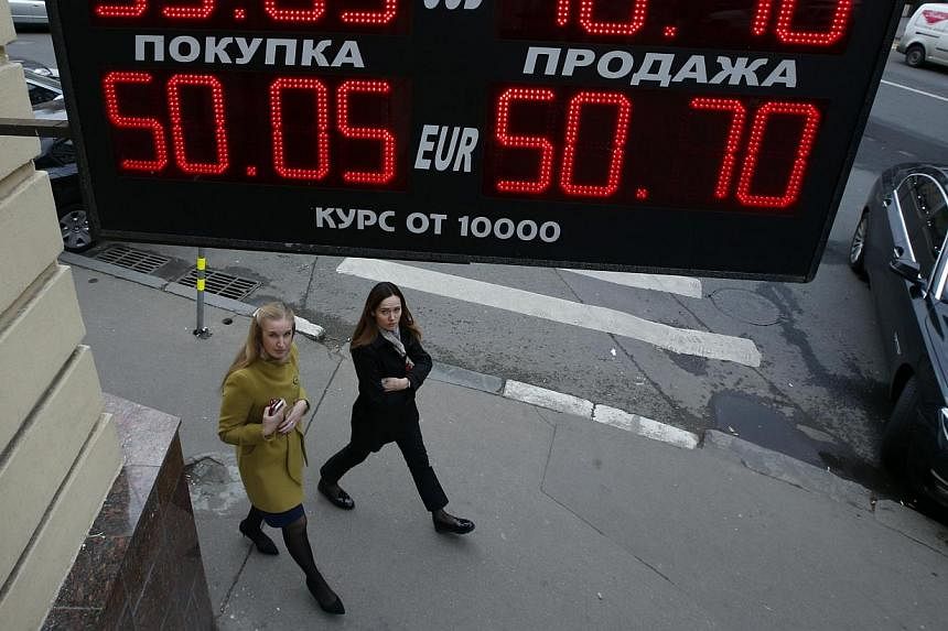 Women walk past a building under a board showing currency exchange rates in Moscow, Oct 7, 2014.&nbsp;Only one top executive in eight at major financial services firms is a woman and the pace of change at banks and other companies is too slow, accord