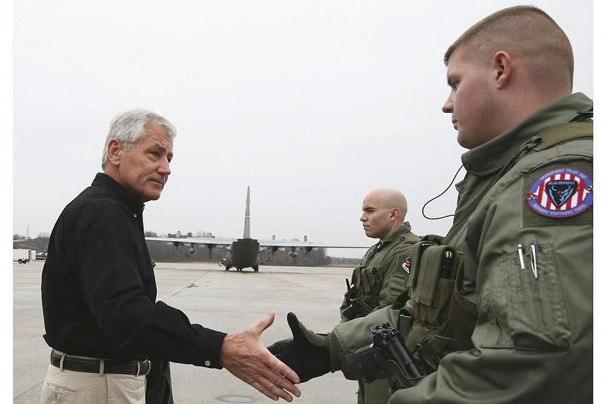 US Secretary of Defense Chuck Hagel (left) greets two members of the US Air Force before boarding his aircraft to departing on an overseas trip at Joint Base Andrews, Maryland on Dec 5, 2014.&nbsp;An additional 1,000 US troops will remain in Afghanis