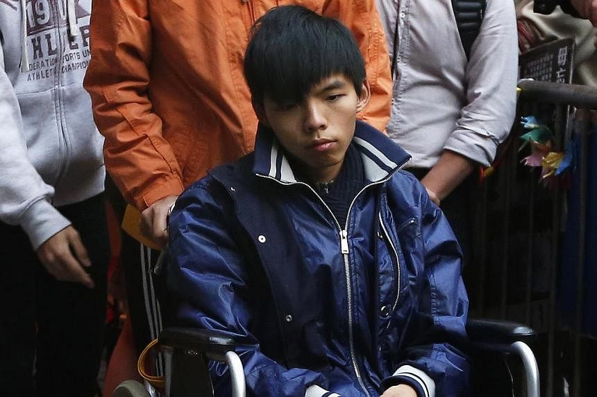 Student leader Joshua Wong, who has undergone more than 90 hours on a hunger strike, sits in a wheelchair as he meets journalists outside the government headquarters in Hong Kong on Dec 5, 2014. -- PHOTO: REUTERS