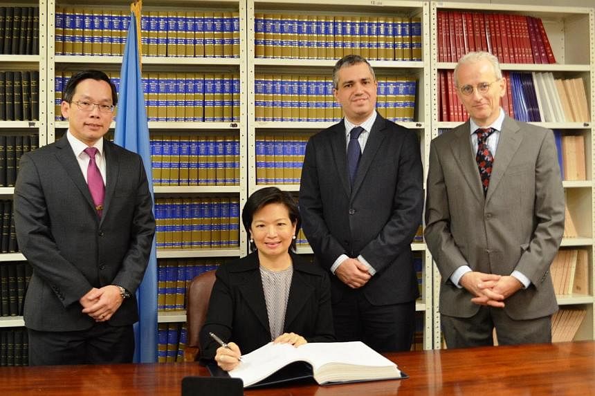 The Permanent Representative of Singapore to the United Nations, Ms Karen Tan (seated), signing the Arms Trade Treaty at the UN Office of Legal Affairs. -- PHOTO: MINDEF&nbsp;