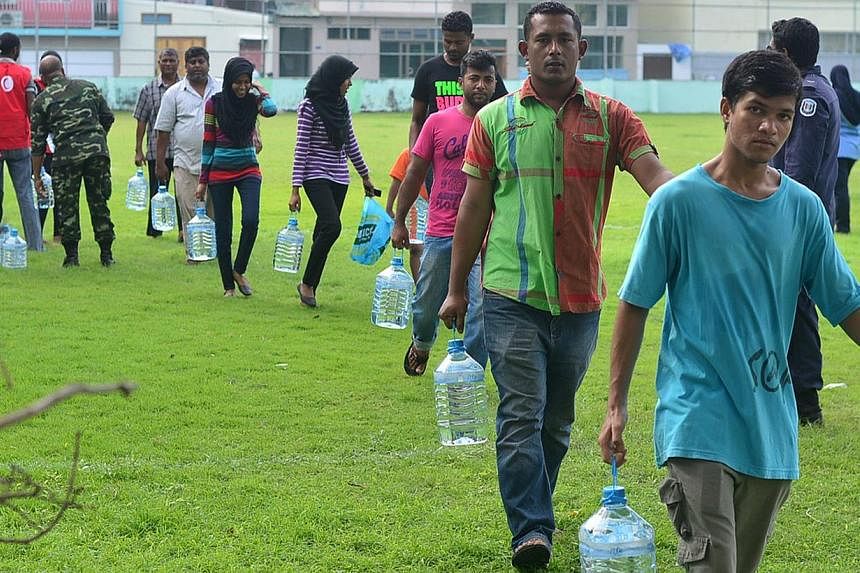 Maldives residents carry their supply of water distributed by Red Crescent and security personnel after a fire at a desalination plant affected water supplies in Male, on Dec 5, 2014. Drinking water had to be airlifted into the Maldivian capital Dec 