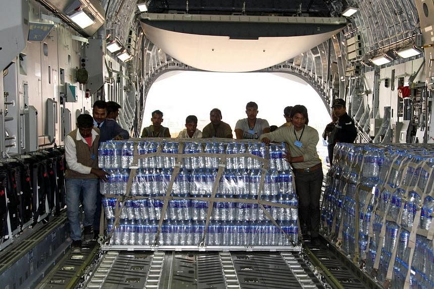 Indian workers and air force personnel load emergency supplies of bottled water onto a Boeing C-17 heavy transport aircraft, bound for the Maldives after a fire at a desalination plant affected water supplies in Male, in New Delhi, on Dec 5, 2014. --
