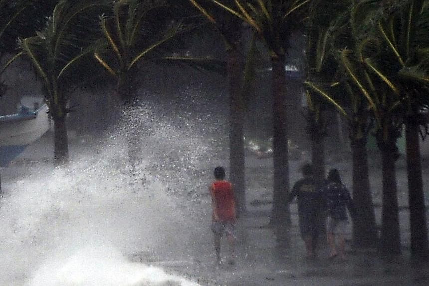 Residents walk past high waves brought about by strong winds as it pound the seawall, hours before Typhoon Hagupit passes near the city of Legazpi on Dec 7, 2014. Typhoon Hagupit tore apart homes and sent waves crashing through coastal communities ac