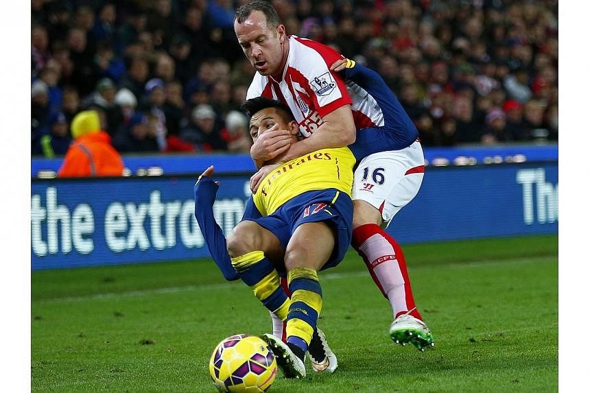 Stoke City's Charlie Adam (top) gets a yellow card for this foul on Arsenal's Alexis Sanchez during their English Premier League football match in Stoke, northern England on Dec 6, 2014. -- PHOTO: REUTERS