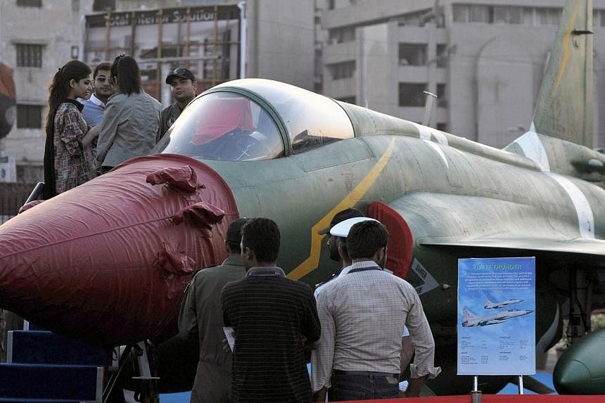 Visitors look at a PAC JF-17 Thunder multirole combat aircraft, conceived and initially developed with the help of China, on static display at the International Defence Exhibition and seminar (IDEAS) in Karachi on Dec 3, 2014.&nbsp;A revamped version