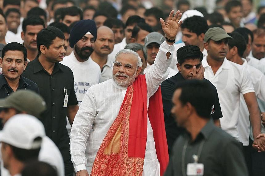 Indian Prime Minister Narendra Modi (centre, wearing orange shawl) waves as he takes part in a run for unity after flagging it off to mark the birth anniversary of Indian freedom fighter and a lawmaker Sardar Vallabhbhai Patel, in New Delhi on Oct 31