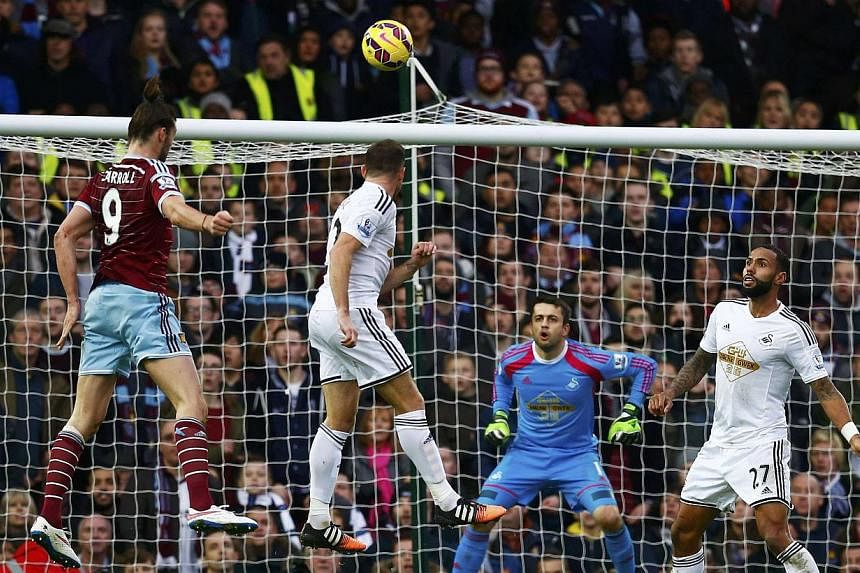 Andy Carrol (left)l of West Ham United heads to score against Swansea City during their English Premier League match against Swansea at Upton Park in London on Dec 7, 2014. -- PHOTO: REUTERS