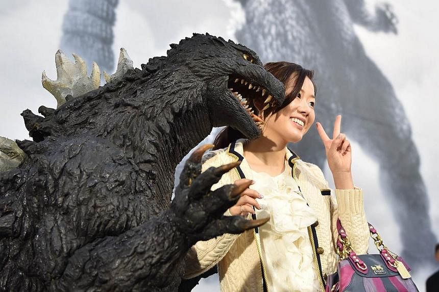 Japan's star monster Godzilla (front left) poses with a fan after an awards ceremony at Toho Studio in Tokyo's Setagaya Ward on Nov 3, 2014. -- PHOTO: AFP