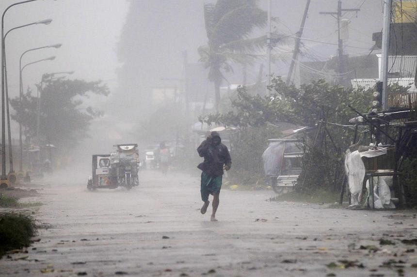 A man walks on a street while strong winds and heavy rain, brought by typhoon Hagupit, batter Atimonan town, Quezon province, south of Manila on Dec 8, 2014.&nbsp;A typhoon that struck the Philippines over the weekend has claimed at least 21 lives, t