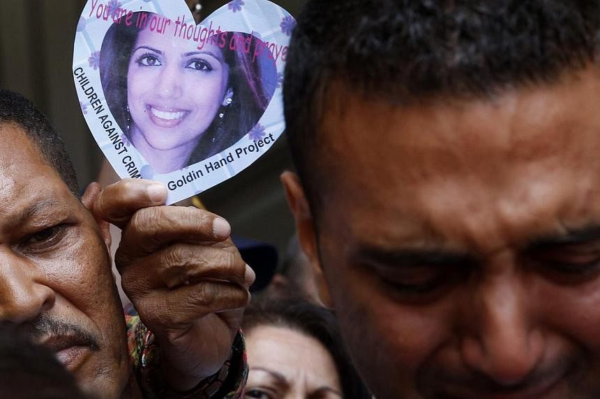 A supporter holds a picture of Anni Dewani as Anni's brother Anish Hindocha (right) leaves a court with family members in Cape Town on Dec 8, 2014.&nbsp;-- PHOTO: REUTERS
