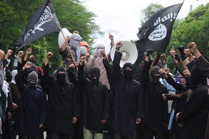 In this file photograph taken on June 9, 2013, masked Indonesian Islamic militant waving the flag of Islamic State, seen at right, stage a rally against Syria's President Bashar al-Assad in Solo located in central Java island where they signified the