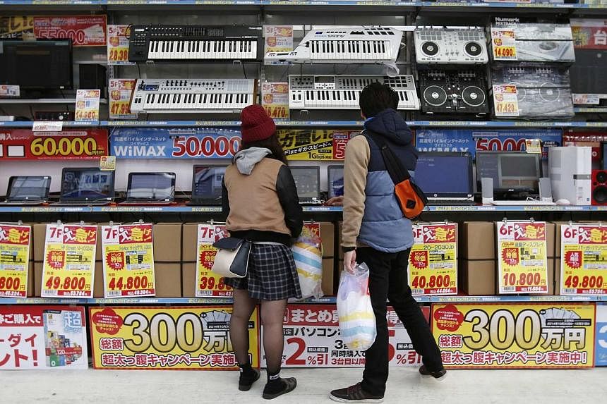People try out laptops displayed at an electronics retail store in Tokyo on Nov 16, 2014. Japan releases its final 3Q GDP data on Monday. -- PHOTO: REUTERS