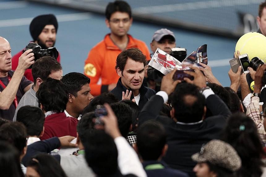 Roger Federer (centre) of the Micromax Indian Aces signs autograph after winning his men's single match against Tomas&nbsp;Berdych of the Singapore Slammers at the International Premier Tennis League in New Delhi on Sunday. -- PHOTO: REUTERS