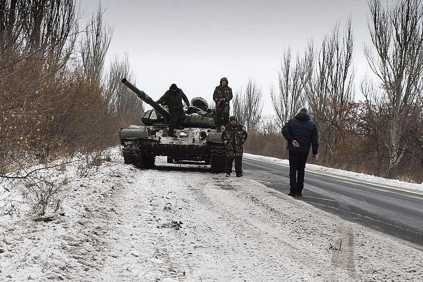 Donestk People's Republic (DNR) fighters stand by their tank on Dec 7, 2014 in the eastern Ukrainian Donesk region. Eight civilians have been killed in fresh violence in eastern Ukraine, where more explosions and gunfire rang out on two days before t