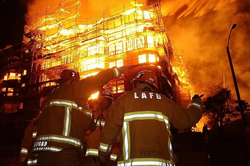 Los Angeles city firefighters battle a massive fire at a seven-story downtown apartment complex under construction in Los Angeles, California on Monday. Over 250 firefighters battle the early morning blaze which shutdown two major freeways. -- PHOTO: