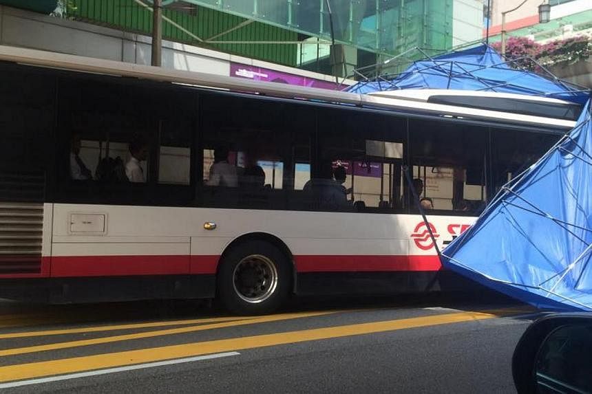 A makeshift tent was displaced from an elevated position and landed on a SMRT bus in Chinatown on Tuesday afternoon. -- PHOTO: FACEBOOK