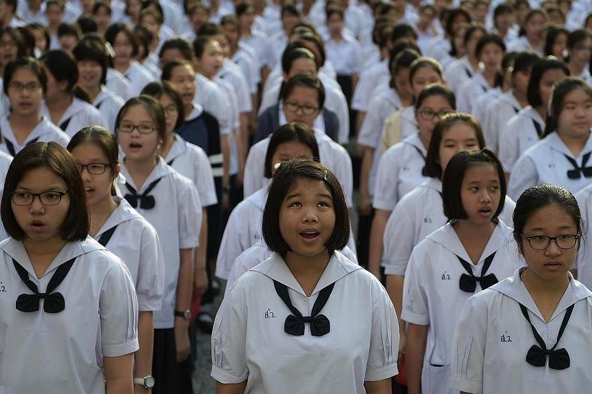 This picture taken on Dec 2, 2014 shows Thai female students standing in lines as they sing the national anthem in the courtyard of the Satriwithaya school in downtown Bangkok at the start of their school day. Thailand's military rulers are pushing a
