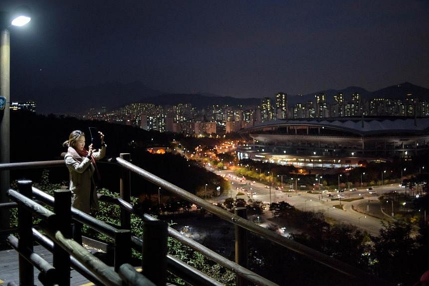 A woman takes pictures of the Seoul city skyline. South Korea's top government think-tank cut its economic growth forecasts for this year and next. --PHOTO: AFP&nbsp;
