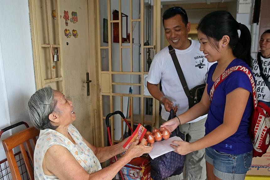 Mr Mervyn Chua, 48, and his daughter Ryen, 12, distributing food to Madam Liow Mee Yin, 75, as well as other elderly folk living alone in Jalan Kukoh. The Chuas are members of Friends in Charity, an informal group of volunteers who give food and cash