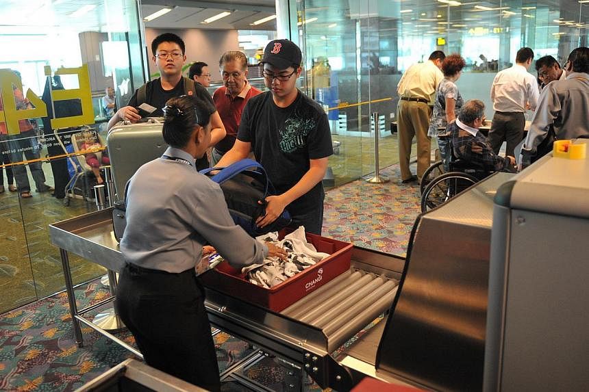 Passengers at Changi Airport Terminal 2 have their hand luggage screened before boarding an aircraft, on Sept 7, 2011. -- PHOTO: ST FILE&nbsp;