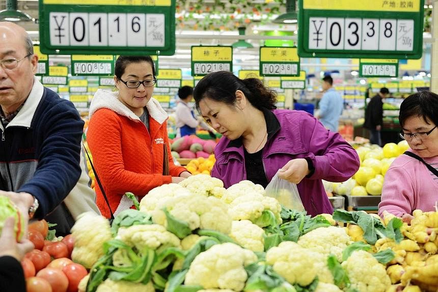 Customers choose vegetables in a market in Qingdao, east China's Shandong province, on Nov 10, 2014. -- PHOTO: AFP