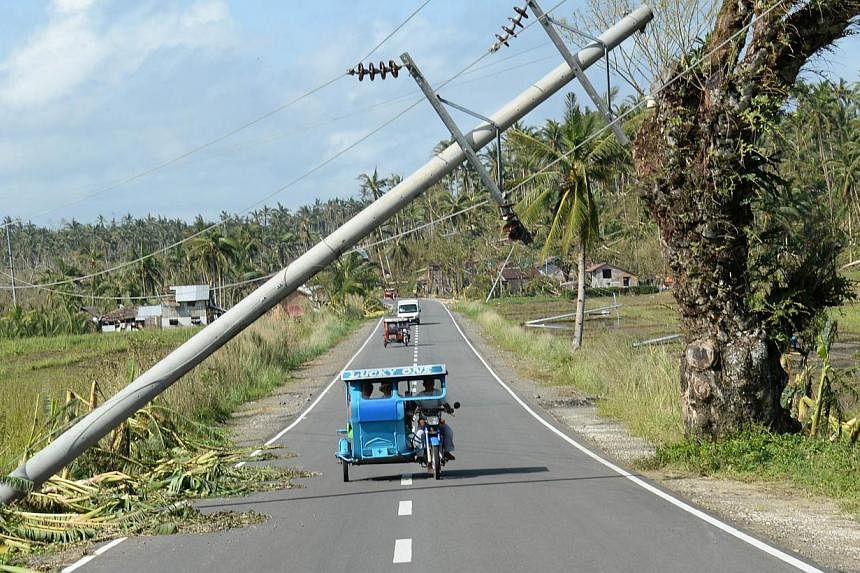A tricycle speeds past a fallen electric pylon destroyed by Typhoon Hagupit along the national highway in San Julian town, Eastern Samar province, on Dec 9, 2014. A joint congressional panel has approved a 15 per cent increase in the government's nat