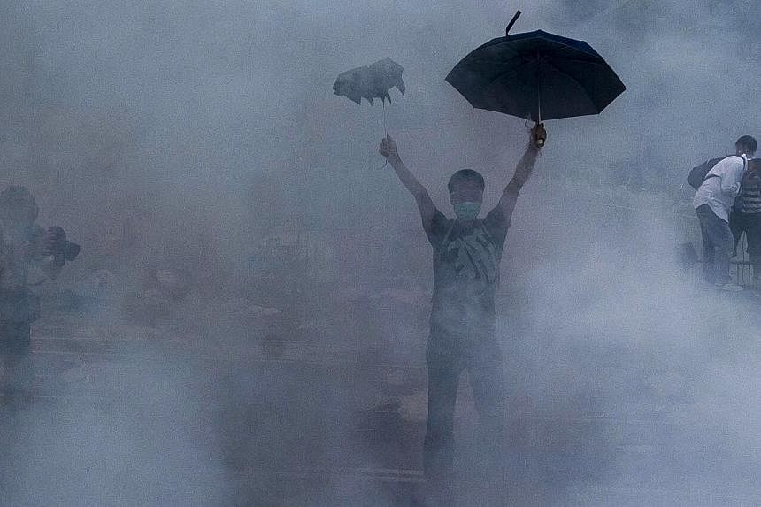 A pro-democracy demonstrator gestures after police fired tear gas towards protesters near the Hong Kong government headquarters on Sept 28, 2014. -- PHOTO: AFP