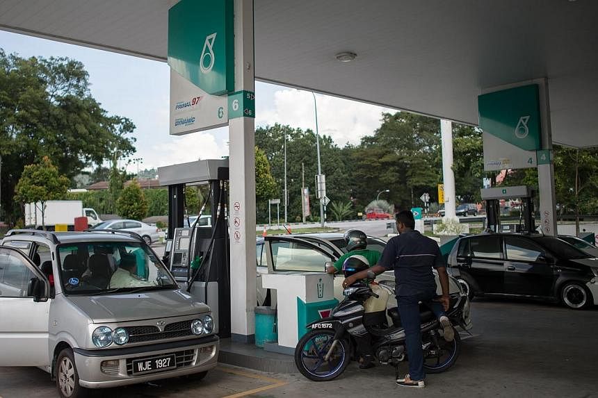 People waiting to refill their vehicles at a Petronas petrol station in Ampang on Nov 28, 2014. Malaysian state oil company Petronas warning last month that its contribution to public coffers could fall from RM68 billion (S$25.8 billion) - which was 